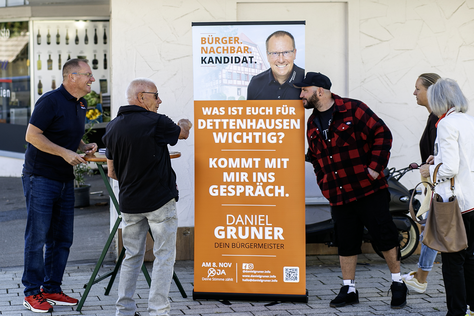 Daniel Gruner im persönlichen Austausch Daniel Gruner betrachtet gemeinsam mit zwei Besuchern Informationsmaterial an einem Stehtisch.