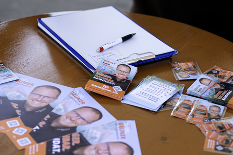 Informationsmaterial von Daniel Gruner Wahlkampfflyer von Daniel Gruner, Kugelschreiber und Schreibunterlagen liegen auf einem Stehtisch.